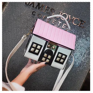 Detailed close-up of a house-shaped handbag featuring pink roof texture and golden twist lock