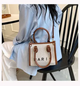 Foto de estilo de vida de un bolso de lona beige con logo PARIS y correa de cuero