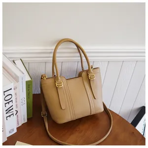 Close-up of khaki pebbled leather bucket bag with gold hardware on wooden surface