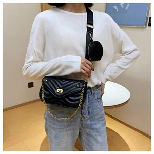 Detail van zwarte gewatteerde crossbodytas met brede riem en rond klein portemonneetje