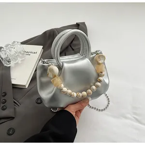 Détail du sac nuage argenté plissé avec chaîne en perles d'ambre et bandoulière en métal