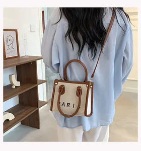 Detalle de mini bolso tote de lona con estampado Paris y ribete de cuero marrón en modelo