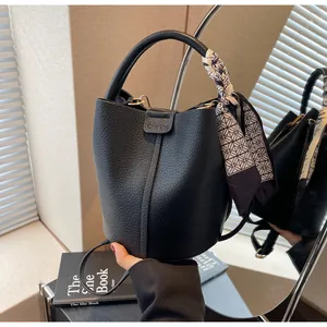 Detail of black pebbled leather bucket bag with silk scarf on handle and Ohio 2nd logo