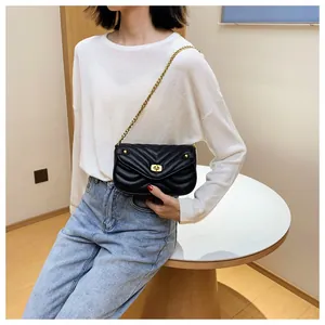 Détail d'un sac bandoulière matelassé noir avec chaîne dorée et fermoir rotatif chic