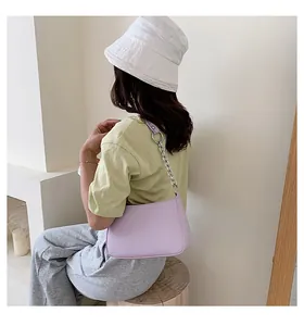 Detalle de un bolso baguette lavanda con cadena plateada sobre el hombro de una modelo