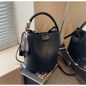 Macro shot of black bucket bag featuring litchi leather texture and vintage silk scarf detail