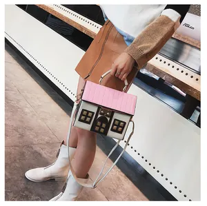 Detail shot of creative house-shaped crossbody bag with pink striped roof and brown leather accents