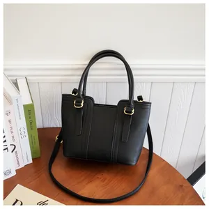 Close-up of black pebble leather tote bag with gold hardware on a wooden table