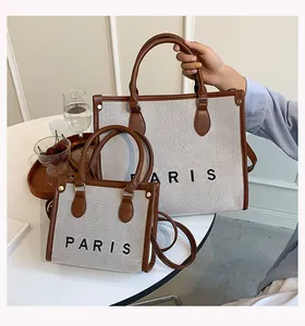 Detalle del conjunto de bolsos de lona con ribetes de cuero marrón y texto Paris