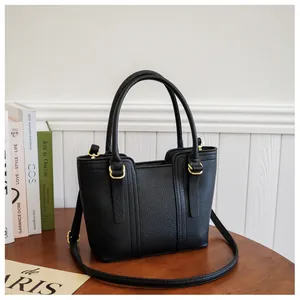 Detail view of black lychee grain leather bucket bag with gold D-ring and crossbody strap