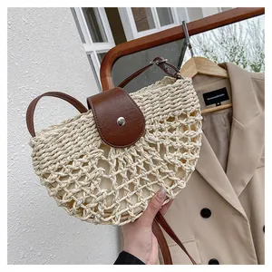 Détail du sac en paille demi-lune avec texture en maille et rabat en cuir marron