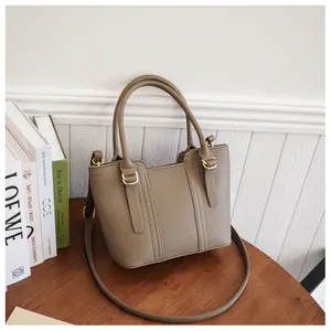 Close-up of pebble leather texture and golden metal hardware on a brown bucket bag