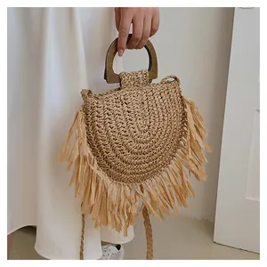 Détail du sac à main en paille tressé avec de longues franges et anse en bois foncé