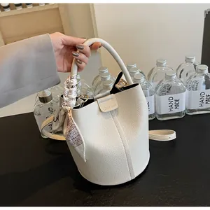 Detail of white bucket bag with pebble leather texture and decorative scarf handle