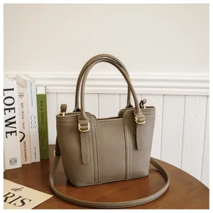 Detailed close-up of khaki pebbled leather texture and stitching on an elegant tote bag