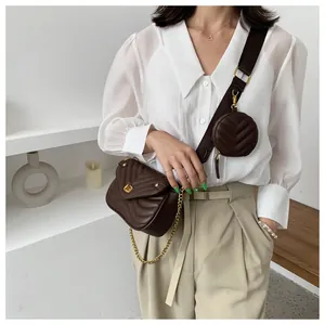 Détail d'un sac bandoulière matelassé marron foncé avec large sangle et petit porte-monnaie