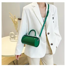 Detail of glossy green cylindrical handbag featuring silver zipper and slim shoulder strap