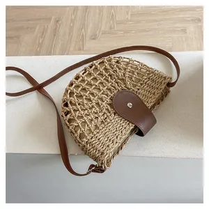 Détail d'un sac bandoulière en paille avec lanière en cuir marron et fermoir magnétique