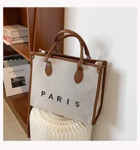 Primer plano de bolso de lona con ribete de cuero marrón e impresión PARIS en el bolso