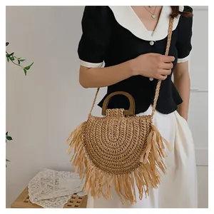 Détail d'un sac à main en paille tressée avec de longues franges et anse en bois