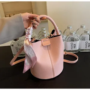 Close-up of pink lychee leather bucket bag with geometric silk scarf and top handle