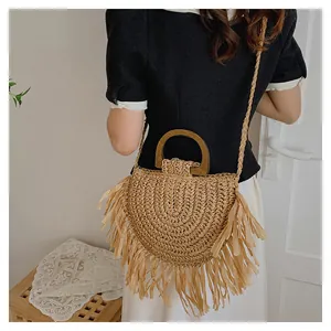 Détail du sac en paille avec bords à franges et poignée en bois porté par un mannequin