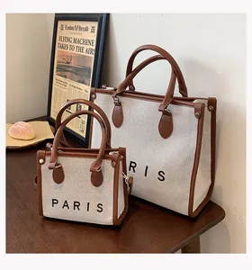 Detalle de bolsos tote de lona crema y cuero marrón en dos tamaños con estampado Paris