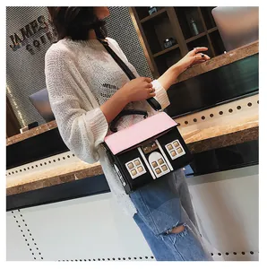 Detailed view of creative house-shaped crossbody bag with pink accents and top handle