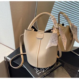 Detail of beige bucket bag with lychee grain leather and silk scarf handle decoration