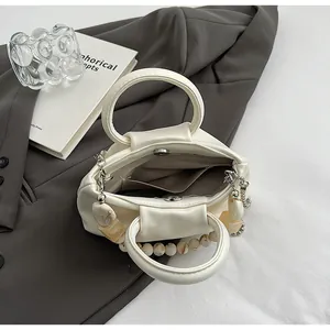 Vue détaillée du sac crème plissé avec fermeture magnétique et doublure à rayures