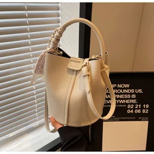 Detail of cream bucket bag with lychee texture leather and decorative silk scarf handle