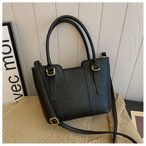 Detail of black lychee texture handbag with gold metal rings and thin shoulder strap