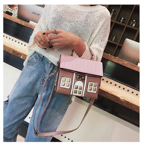 Detail of creative house-shaped crossbody bag with pink roof and gold metal clasp