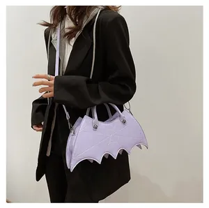 Lavender bat-shaped crossbody bag with spider web stitching worn on a black blazer