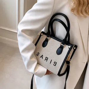 Minimalist canvas tote with black leather trim and PARIS text shown on a white blazer