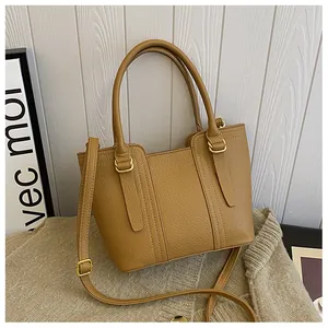 Detail of light brown lychee grain leather handbag with gold hardware on knit fabric