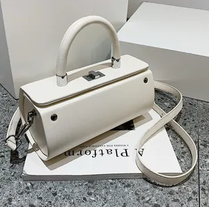 Minimalist beige cylinder handbag with silver twist lock and detachable crossbody strap
