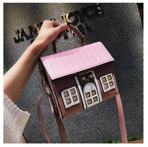 Close-up of a house-shaped pink and brown handbag with a golden metal twist lock
