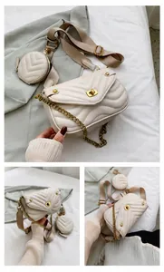 Détail d'un sac matelassé crème avec bandoulière large et pendentif porte-monnaie rond