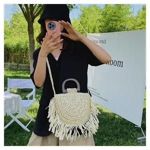 Détail d'un sac à bandoulière en paille bohème avec franges et poignée en bois
