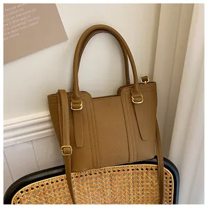 Detail of a brown lychee pattern leather bucket bag with gold hardware and shoulder strap