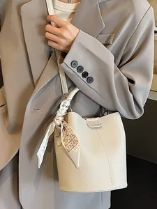 White lychee leather bucket bag with decorative silk scarf and chic top handle