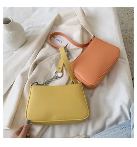 Detalle de bolsos baguette amarillos y naranjas con cadenas de plata en traje beige