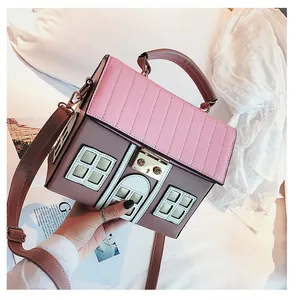 Detail showing pink stitched roof and metal gold lock on a house-shaped handbag