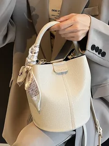 Elegant white bucket bag in textured leather with decorative scarf and shoulder strap