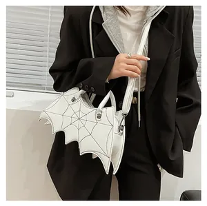 Detail of white bat-shaped crossbody bag featuring cobweb embroidery and spider charm