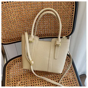 Detail of cream lychee texture handbag on a vintage rattan chair with gold hardware