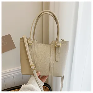 Close-up of cream pebble leather bucket bag showing golden hardware and stitching