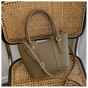 Detail of khaki green pebble leather handbag with dual handles on a vintage rattan chair