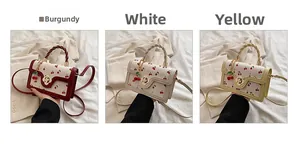 Three elegant leather handbags in wine red, white, and yellow with cherry charms